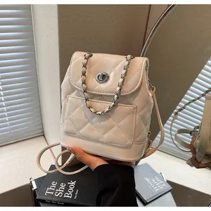 Gros plan d'un mini sac à dos matelassé crème avec chaîne argentée et fermoir pivotant.