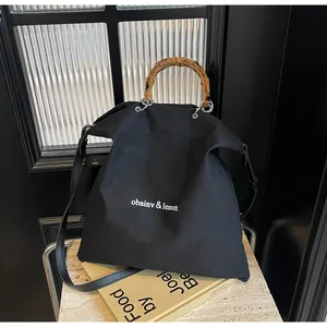 Detailed shot of black canvas tote with natural bamboo handles and white text print