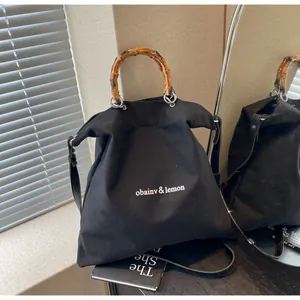 Elegant black canvas tote bag featuring natural bamboo handles in a lifestyle setting.