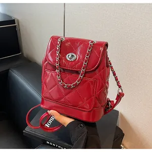 Détail d'un sac à dos rouge en cuir verni matelassé avec chaîne argentée