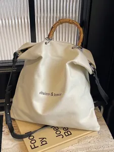 Elegant large capacity canvas tote bag with iconic bamboo handle and black strap