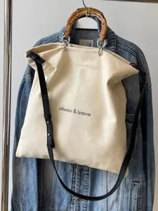 Large canvas tote bag with bamboo handles and black strap for casual summer style