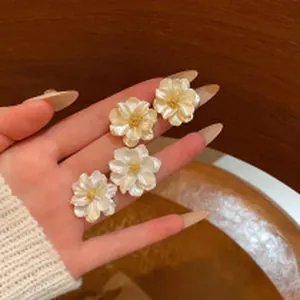 Close-up of white sunflower stud earrings with gold centers held in hand for detail