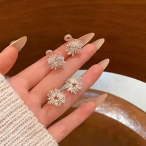 Close-up of sparkling sunflower stud earrings with radiant crystal petals on a hand.