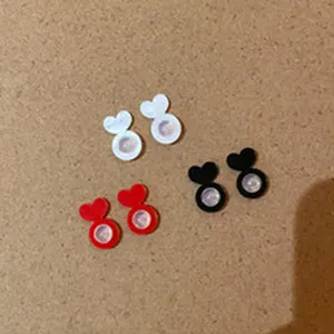 Close-up view showing heart-shaped earring backs in white, red, and black colors on brown base.