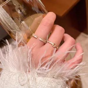 Close-up of elegant gold zircon open ring and thin band on finger with soft feather