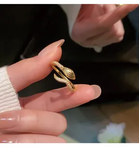 Detailed macro view of a gold-plated snake-shaped open ring featuring micro-pave crystals