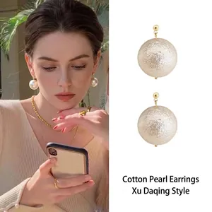 Detail view of large textured cotton pearl drop earrings with elegant golden stud
