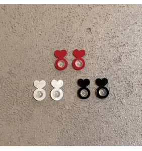 Detailed view of heart-shaped silicone earring backs in red, white, and black colors.