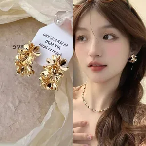 Macro detail of elegant golden layered flower earrings shown on card and worn by model