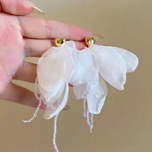 Close-up of elegant white organza petal earrings featuring gold heart-shaped studs