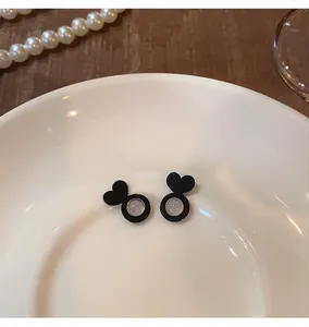 Macro detail of black heart shaped silicone earring backs on a white ceramic plate