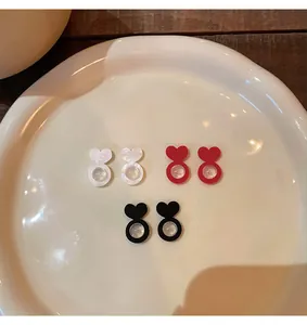 Heart-shaped silicone earring backs in pearl white, red, and black shown on a white plate.