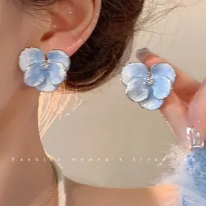 Close-up detail of these elegant blue flower-shaped stud earrings with silver-toned edges.