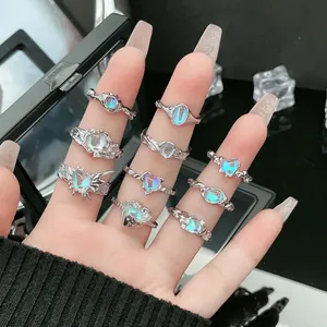 Close-up van vloeibare zilveren ringen met stralende blauwe maanstenen om de vingers.