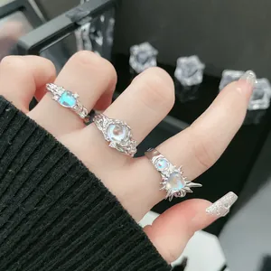 Macroweergave van drie getextureerde zilveren ringen met iriserende maanstenen op een hand