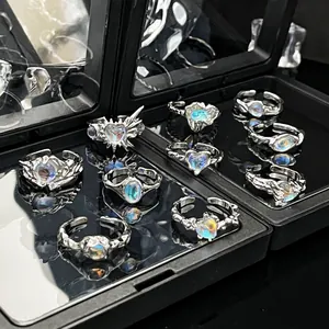 Gedetailleerd overzicht van zilveren open ringen met iriserende maanstenen in zwarte doos