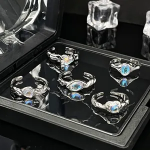 Detail van vijf zilveren vloeibaar metalen ringen met maansteen op een zwarte basis.