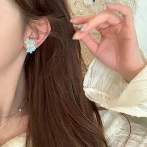 Detailed view of elegant light blue beaded flower stud earrings worn on a model ear