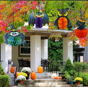 Décorations suspendues en nid d'abeille pour Halloween dans un décor extérieur.
