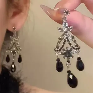 Close-up of vintage silver chandelier earring with black teardrops and sparkling crystals.