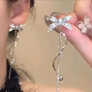 Close-up of sparkling bow-knot tassel earrings with silver finish and wavy drop
