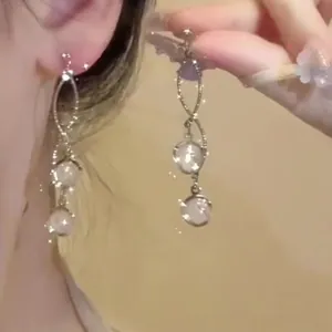 Detailed close-up of elegant sparkling diamond tassel earrings worn by a model