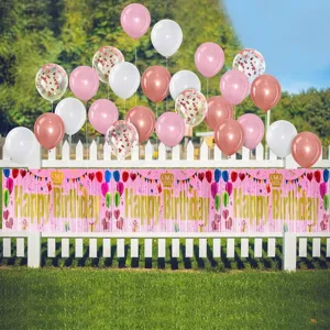 Detail showing pink Happy Birthday fringe banner with assorted balloons on white picket fence