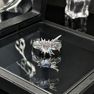 Detailopname van een zilveren ring met stekels en een hartvormige maansteen op zwart