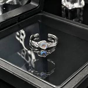 Gedetailleerde weergave van een minimalistische zilveren open ring met maansteen op zwart