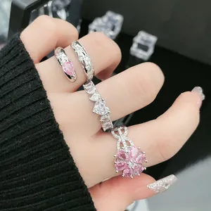 Nahaufnahme von eleganten silberfarbenen Ringen mit rosa Blumen- und Herzsteinen an einer Hand