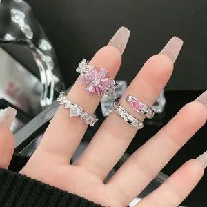 Detaillierte Makroansicht von drei funkelnden rosa und klaren Steinringen an Fingern.