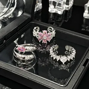 Detailansicht von drei silbernen Ringen mit rosa Blüten- und Herzstein-Akzenten.