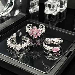 Detailansicht luxuriöser verstellbarer Silberringe mit rosa Zirkonia-Blumen und Herzen.