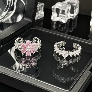 Detaillierte Makroaufnahme von eleganten verstellbaren Ringen mit rosa Blume und Herz-Kristall