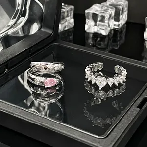 Detaillierte Makroansicht von eleganten Ringen mit rosa Stein und herzförmigen Kristallen