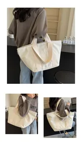 Detailansicht einer cremefarbenen Canvas-Einkaufstasche mit gestickten Buchstaben