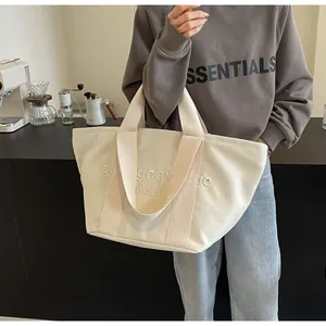 Lifestyle-Detailansicht einer beige Leinentasche mit weißer Buchstabenbestickung