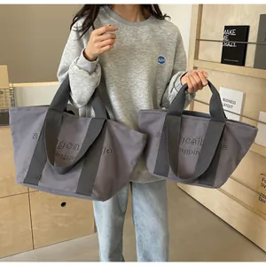 Detailansicht grauer Canvas-Tote-Bags in zwei Größen mit stilvoller Stickerei-Beschriftung