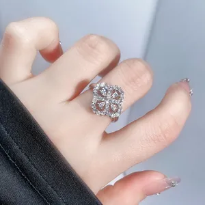 Close-up of a sparkling silver four-leaf clover flower open ring with CZ stones worn on a finger