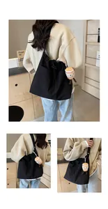 Vista detallada de un bolso tote grande de nailon negro con un adorable colgante de peluche en modelo