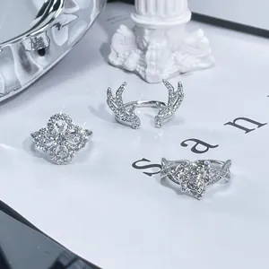 Close-up detail of sterling silver rings with intricate pavé stone antler and clover motifs.