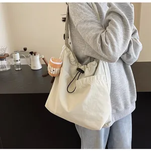 Detail view of large cream nylon tote bag with cute coffee cup charm worn by a model