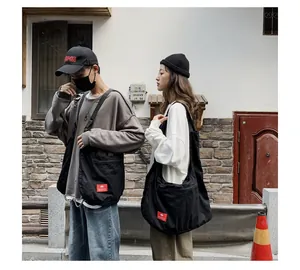 Models wearing black large capacity street style crossbody bags in an urban setting