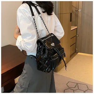 Gros plan d'un sac à dos noir matelassé avec fermoir cœur porté par un mannequin en intérieur.