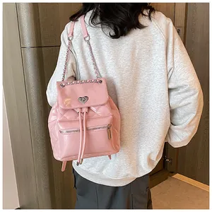 Vue arrière détaillée d'un sac à dos rose en cuir matelassé avec chaînes sur un mannequin