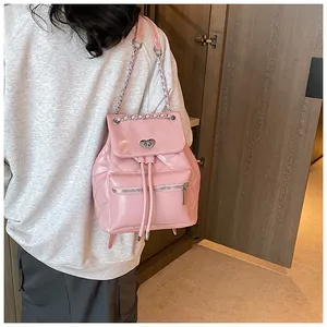 Détail d'un sac à dos rose matelassé avec chaîne et fermoir pivotant en cœur