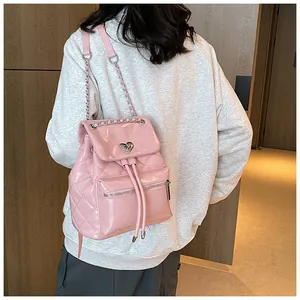 Détail d'un sac à dos rose matelassé avec des sangles en chaîne sur un mannequin.