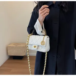 Dettaglio di una borsa a tracolla trapuntata bianca con catena e cappotto nero