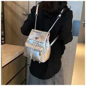 Sac à dos à chaîne matelassé argenté pour femme porté sur le dos avec une tenue noire
